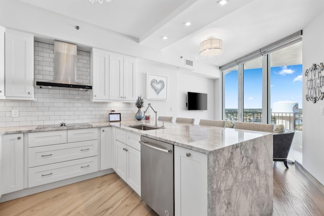 kitchen featuring sink, white cabinetry, stainless steel dishwasher, and wall chimney exhaust hood