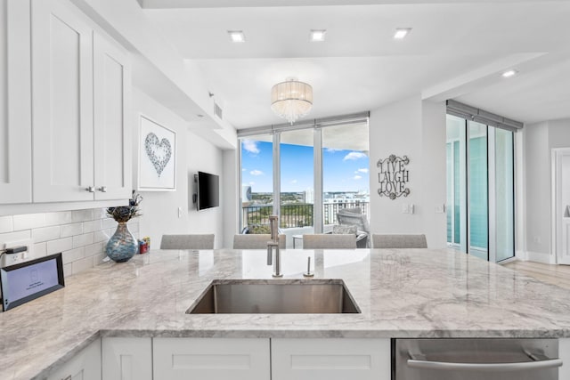 kitchen with light stone countertops, a wealth of natural light, and white cabinetry