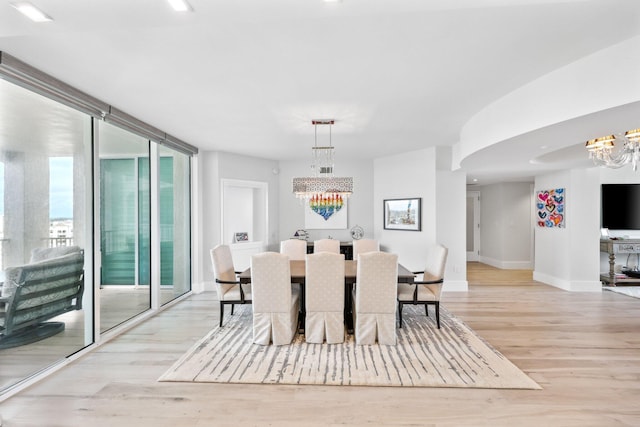 dining space featuring a chandelier, floor to ceiling windows, and light hardwood / wood-style flooring