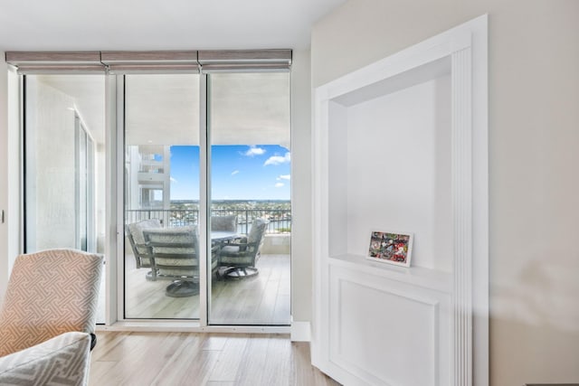 doorway with floor to ceiling windows and light hardwood / wood-style flooring