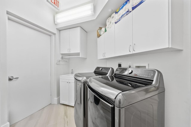 clothes washing area with light wood-type flooring, separate washer and dryer, and cabinets