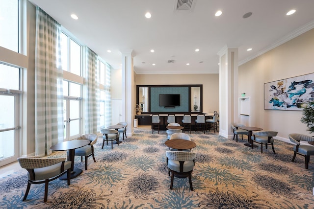 carpeted living room with decorative columns, ornamental molding, and a healthy amount of sunlight