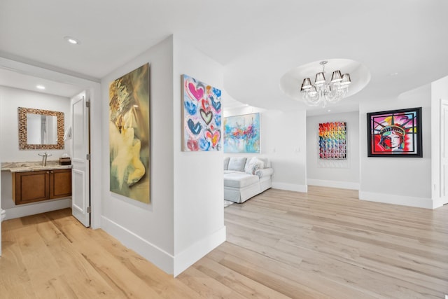 hall featuring a chandelier, light hardwood / wood-style floors, and sink