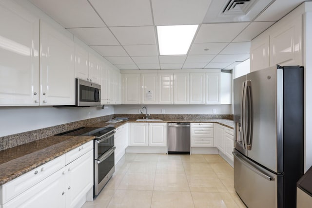 kitchen featuring dark stone countertops, sink, a paneled ceiling, appliances with stainless steel finishes, and white cabinets