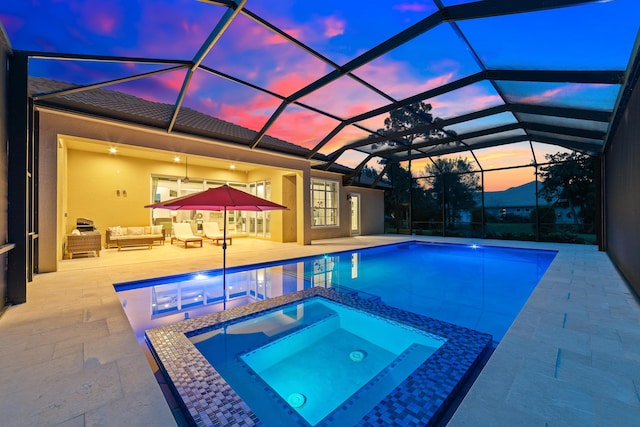 10176 Calabrese Trl, Jupiter, FL 33478 - pool at dusk featuring outdoor lounge area, a patio area, a pool with connected hot tub, and glass enclosure