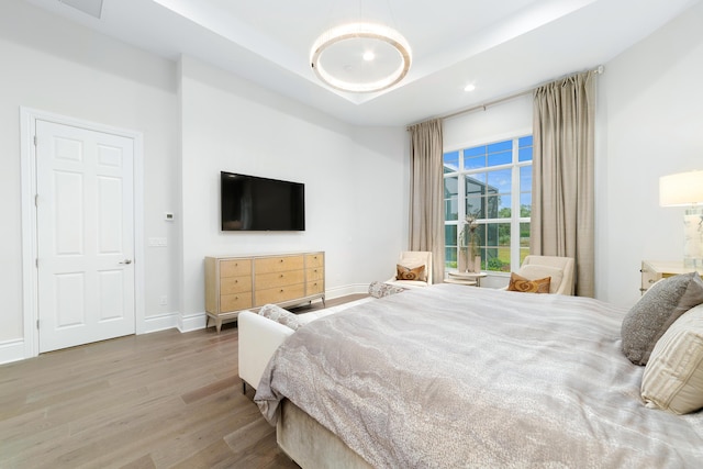 bedroom with hardwood / wood-style flooring and a tray ceiling