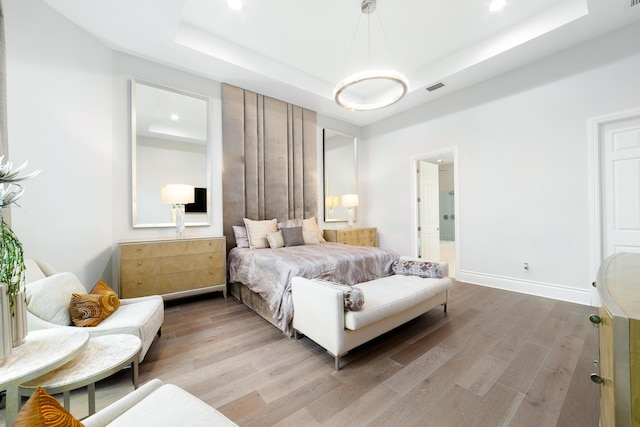 bedroom featuring light hardwood / wood-style floors and a tray ceiling