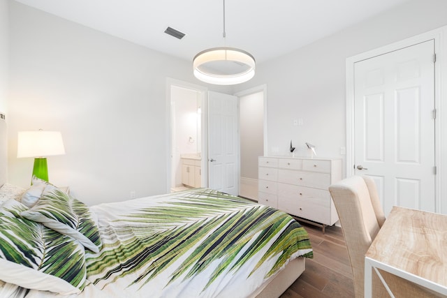 bedroom featuring connected bathroom and dark wood-type flooring