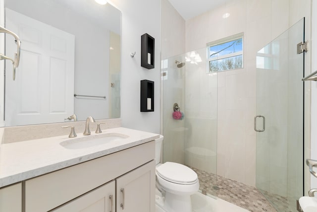 bathroom with toilet, a shower with shower door, and vanity