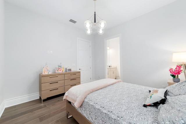 bedroom with dark wood-type flooring, connected bathroom, and an inviting chandelier