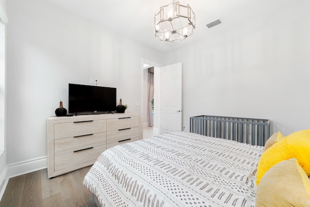 bedroom with light wood-type flooring and a chandelier