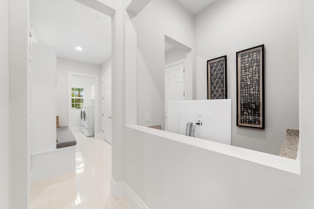 corridor featuring washing machine and dryer and light tile patterned floors