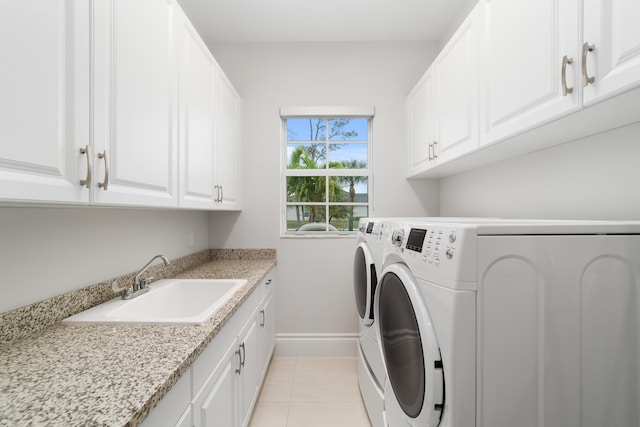 laundry room with sink, washing machine and dryer, light tile patterned floors, and cabinets