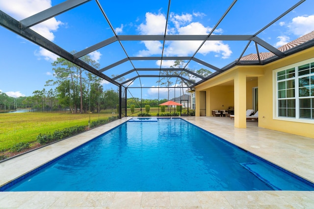 view of pool featuring a patio, glass enclosure, ceiling fan, and a yard