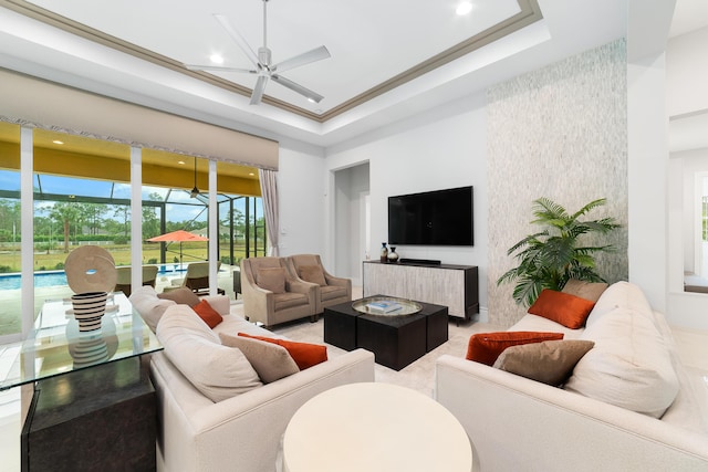 living room with ceiling fan, crown molding, and a tray ceiling