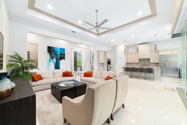 living room with ceiling fan, light tile patterned floors, and a raised ceiling