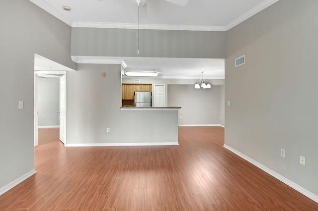 unfurnished living room featuring ceiling fan with notable chandelier, ornamental molding, and hardwood / wood-style floors