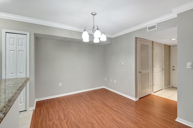 unfurnished dining area featuring ornamental molding, light hardwood / wood-style floors, and a notable chandelier