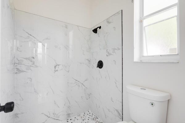 bathroom with tiled shower and toilet