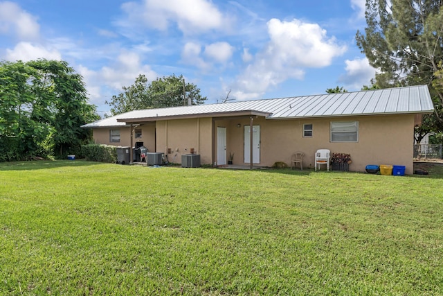 rear view of house featuring cooling unit and a yard