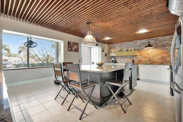 tiled dining space featuring sink and brick wall