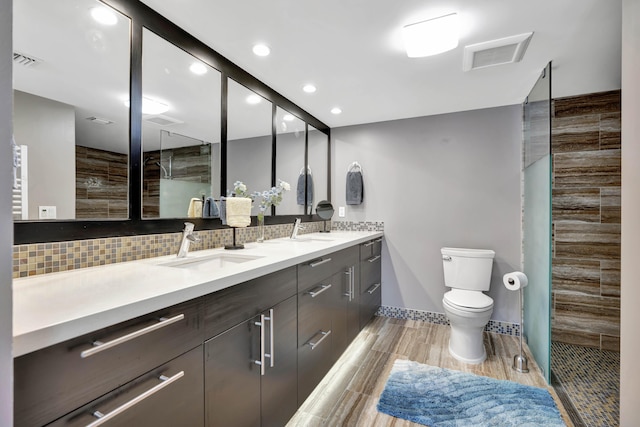 bathroom featuring toilet, hardwood / wood-style flooring, decorative backsplash, walk in shower, and vanity