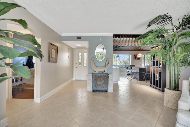 interior space featuring a textured ceiling, light tile patterned floors, and ornamental molding