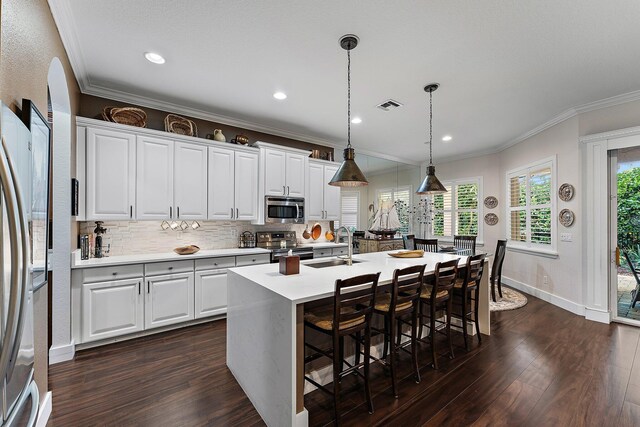 kitchen featuring pendant lighting, stainless steel appliances, an island with sink, white cabinetry, and sink