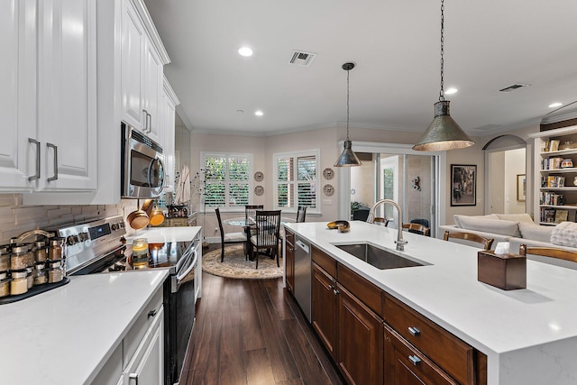 kitchen featuring pendant lighting, sink, stainless steel appliances, white cabinets, and a center island with sink