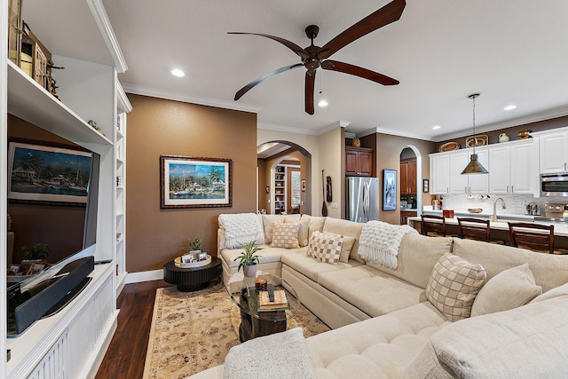 living room with ornamental molding, ceiling fan, and dark hardwood / wood-style floors