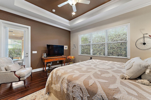 bedroom with crown molding, dark wood-type flooring, ceiling fan, and a tray ceiling