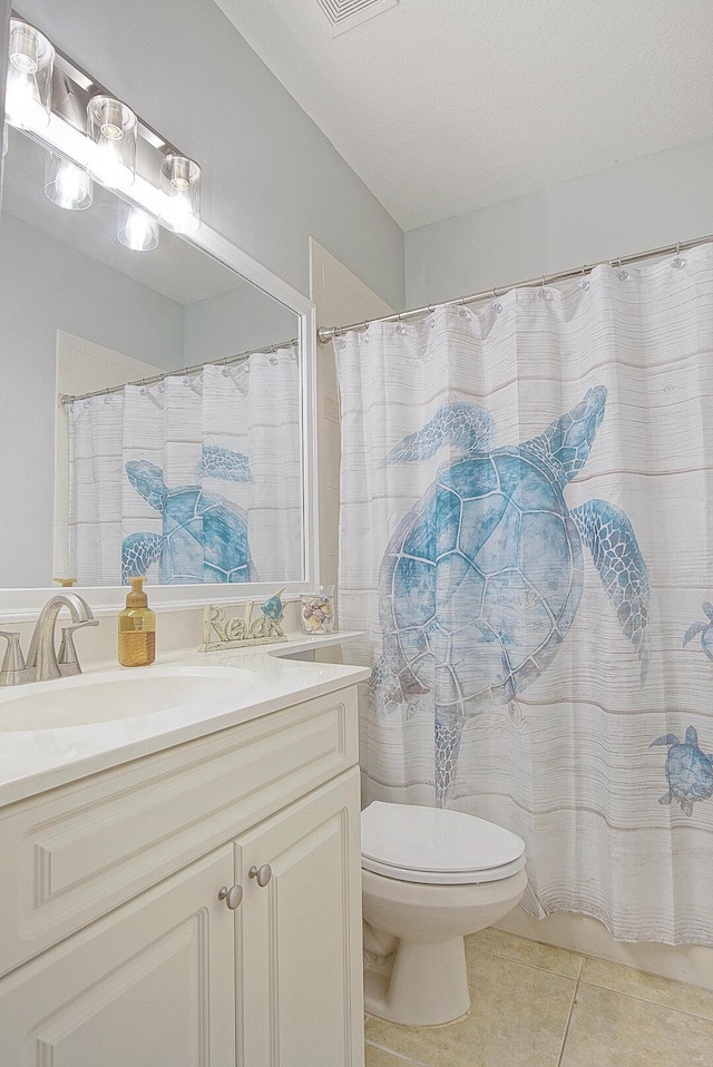 bathroom featuring toilet, tile patterned flooring, walk in shower, and vanity