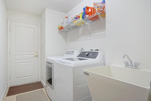 laundry area featuring washing machine and dryer, sink, and a textured ceiling