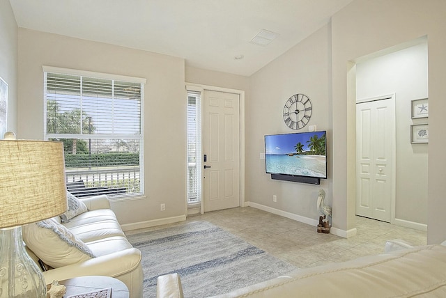 living room with light tile patterned floors and vaulted ceiling