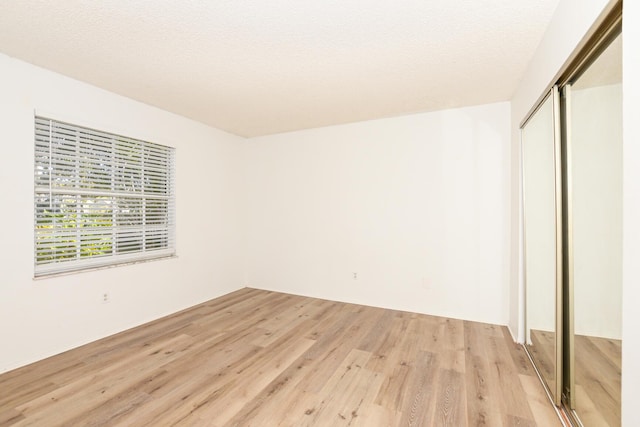 unfurnished bedroom with a closet, a textured ceiling, and light hardwood / wood-style flooring