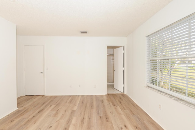 empty room featuring a textured ceiling and light hardwood / wood-style flooring