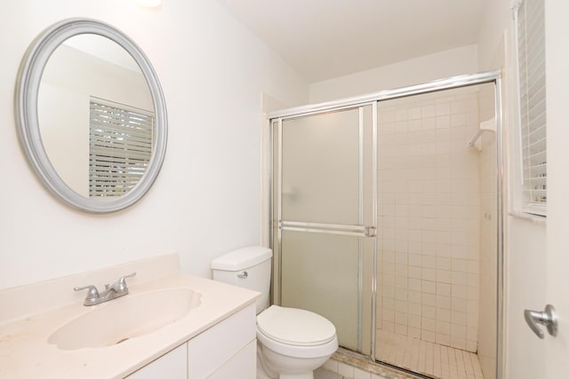 bathroom featuring a shower with door, vanity, and toilet