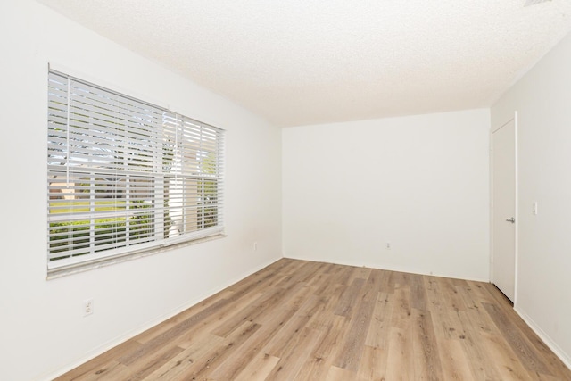 unfurnished room featuring light wood-type flooring and a textured ceiling