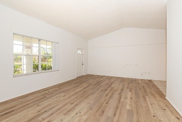 spare room with lofted ceiling and light wood-type flooring