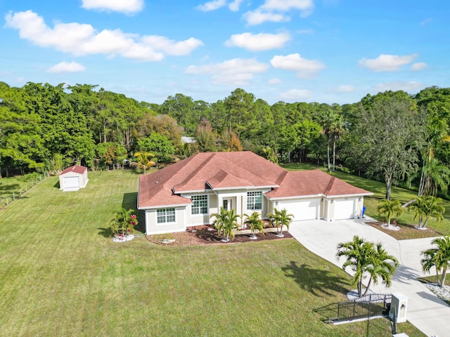 view of front of house featuring a front yard, driveway, an attached garage, and a wooded view