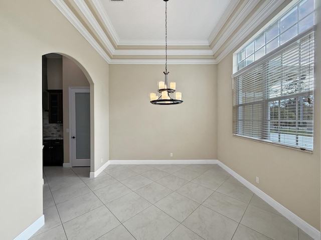 empty room featuring crown molding, light tile patterned floors, a tray ceiling, and a chandelier