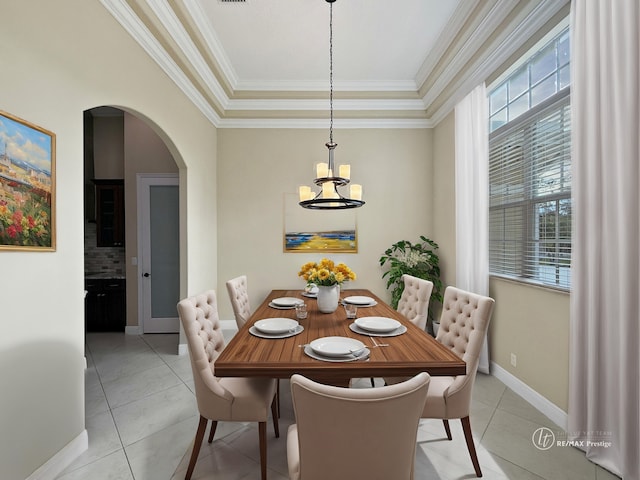 dining room featuring light tile patterned floors, a notable chandelier, ornamental molding, and a raised ceiling