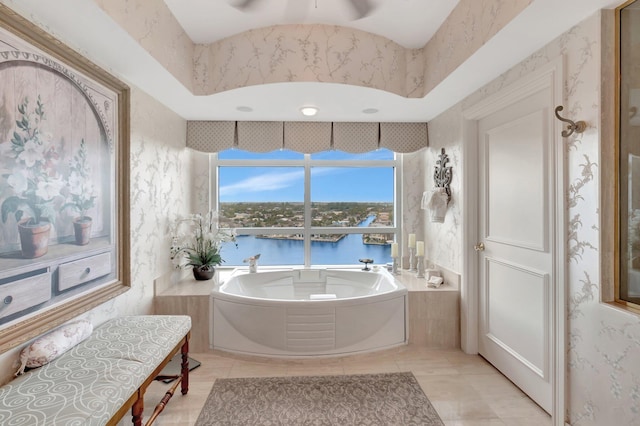 bathroom featuring tiled bath, a water view, tile patterned floors, and ceiling fan