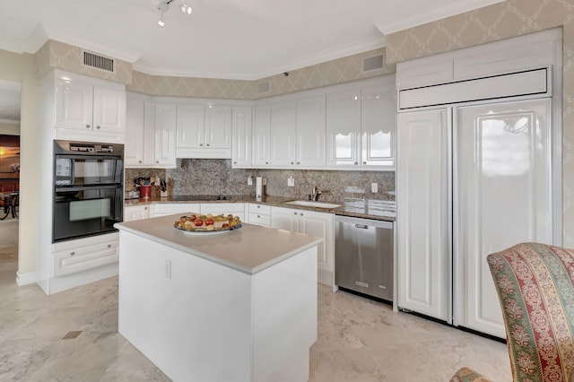 kitchen featuring tasteful backsplash, a kitchen island, black appliances, sink, and white cabinetry