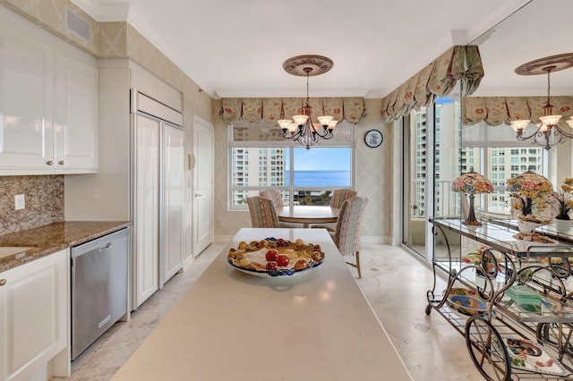 dining space featuring an inviting chandelier, crown molding, a water view, and plenty of natural light