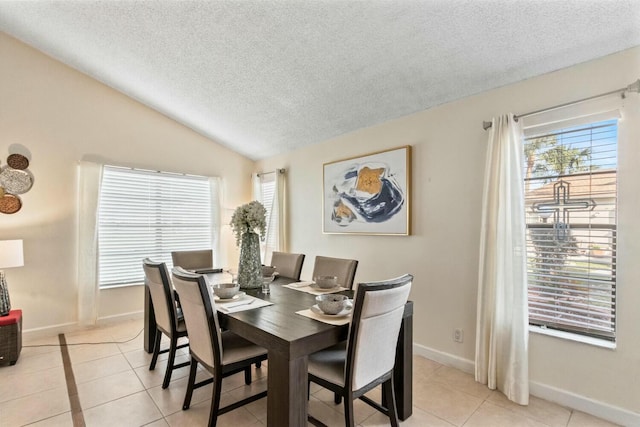 tiled dining area featuring lofted ceiling and a textured ceiling