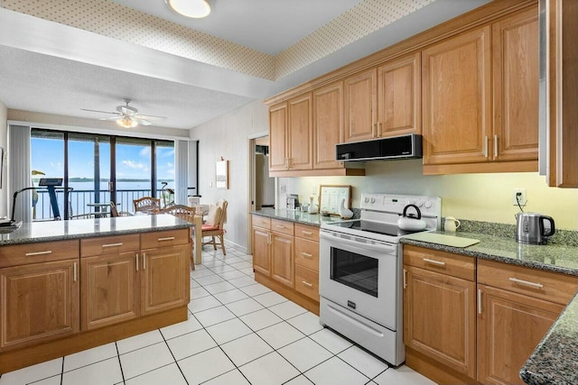 kitchen featuring ceiling fan, light tile patterned floors, electric range, and dark stone countertops