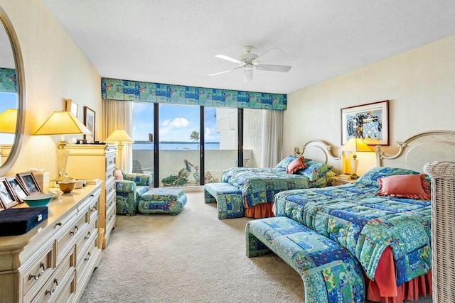 bedroom with light carpet, ceiling fan, access to outside, a textured ceiling, and a water view