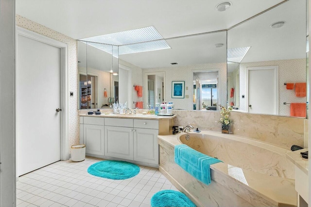 bathroom featuring tiled tub, tile patterned floors, vanity, and a skylight