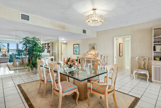 dining area with a textured ceiling, an inviting chandelier, and light tile patterned flooring